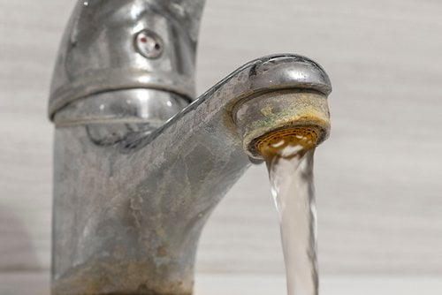 Old Bathroom Sink Faucet Contaminated With Calcium And Grime. Hard Water Flows From An Old Tap Aerator.